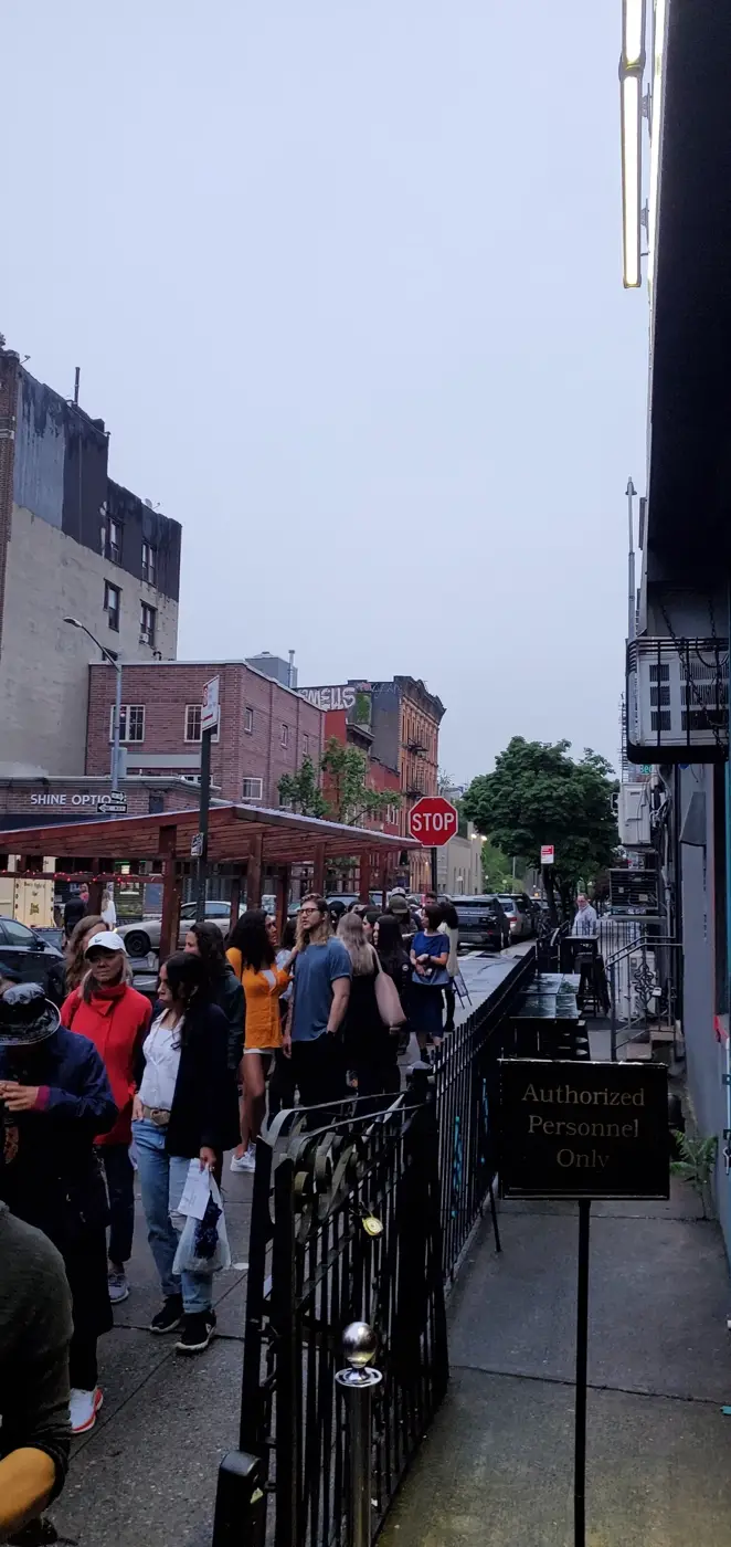 Audience lined up on the sidewalk outside before a comedy show