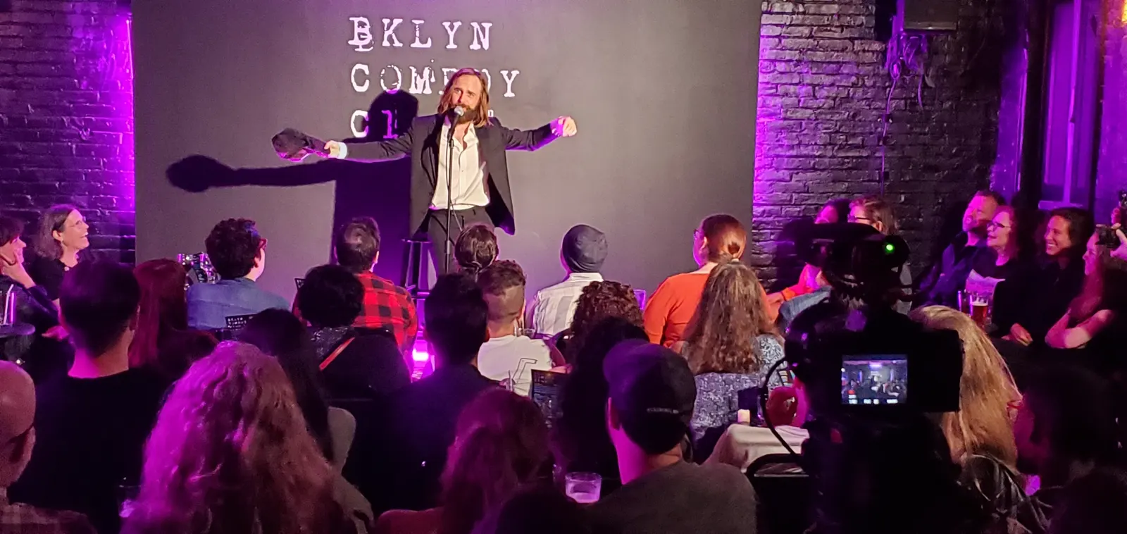 Comedian on stage in front of a packed room at Old Man Hustle BKLYN Comedy Club