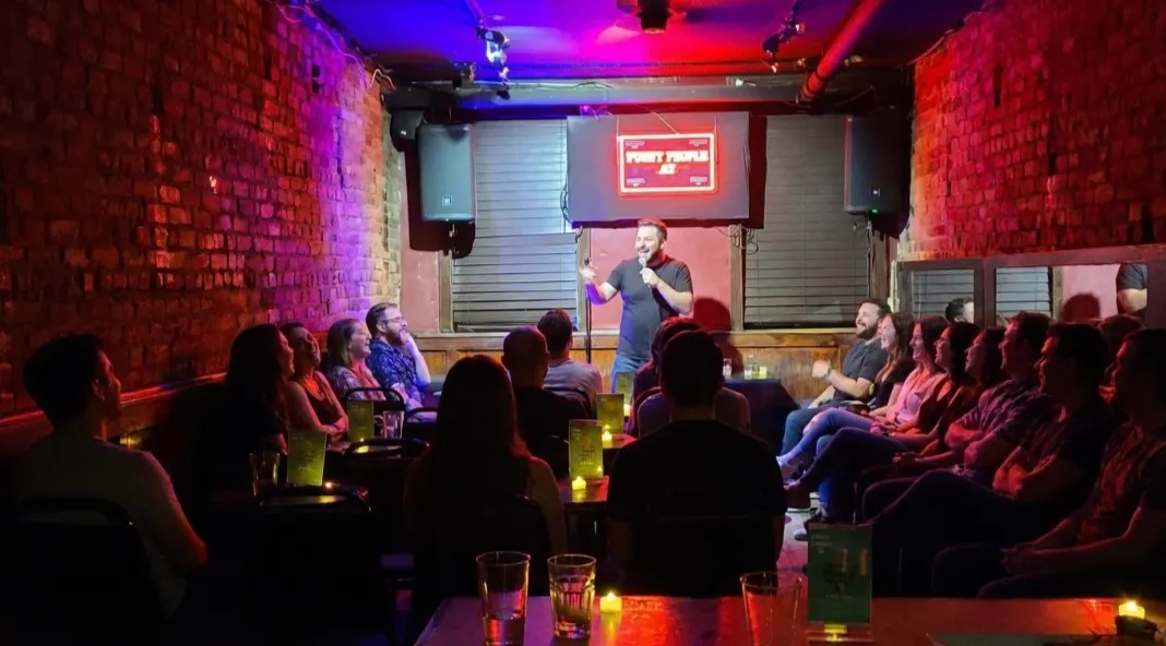Comedian performing on stage in the red-brick 40-seat room at Upper East Side Comedy Club