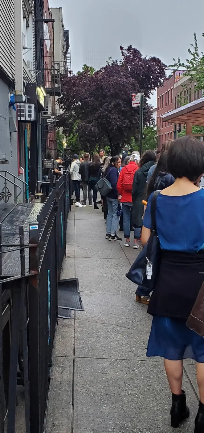 Comedy fans waiting in line along the sidewalk before doors open