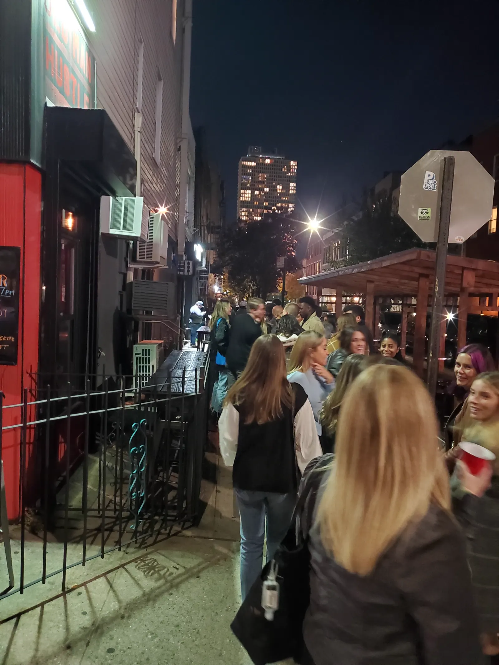 Crowd gathered on the sidewalk outside a comedy show at night