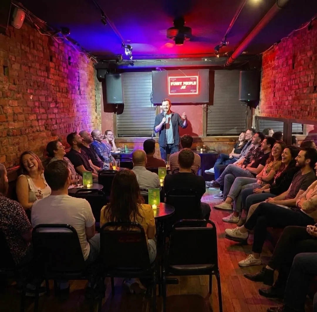 Full house seated at candlelit tables during a comedy show at Upper East Side Comedy Club